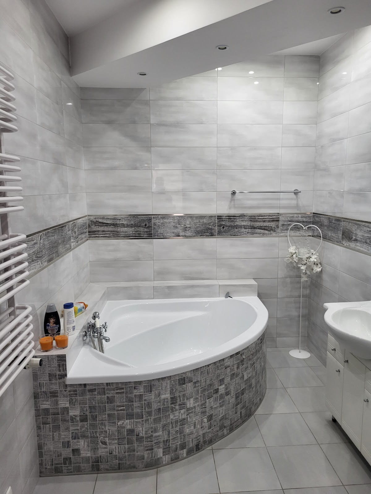 Zadbana łazienka hotelowa z narożną wanną i jasnymi płytkami