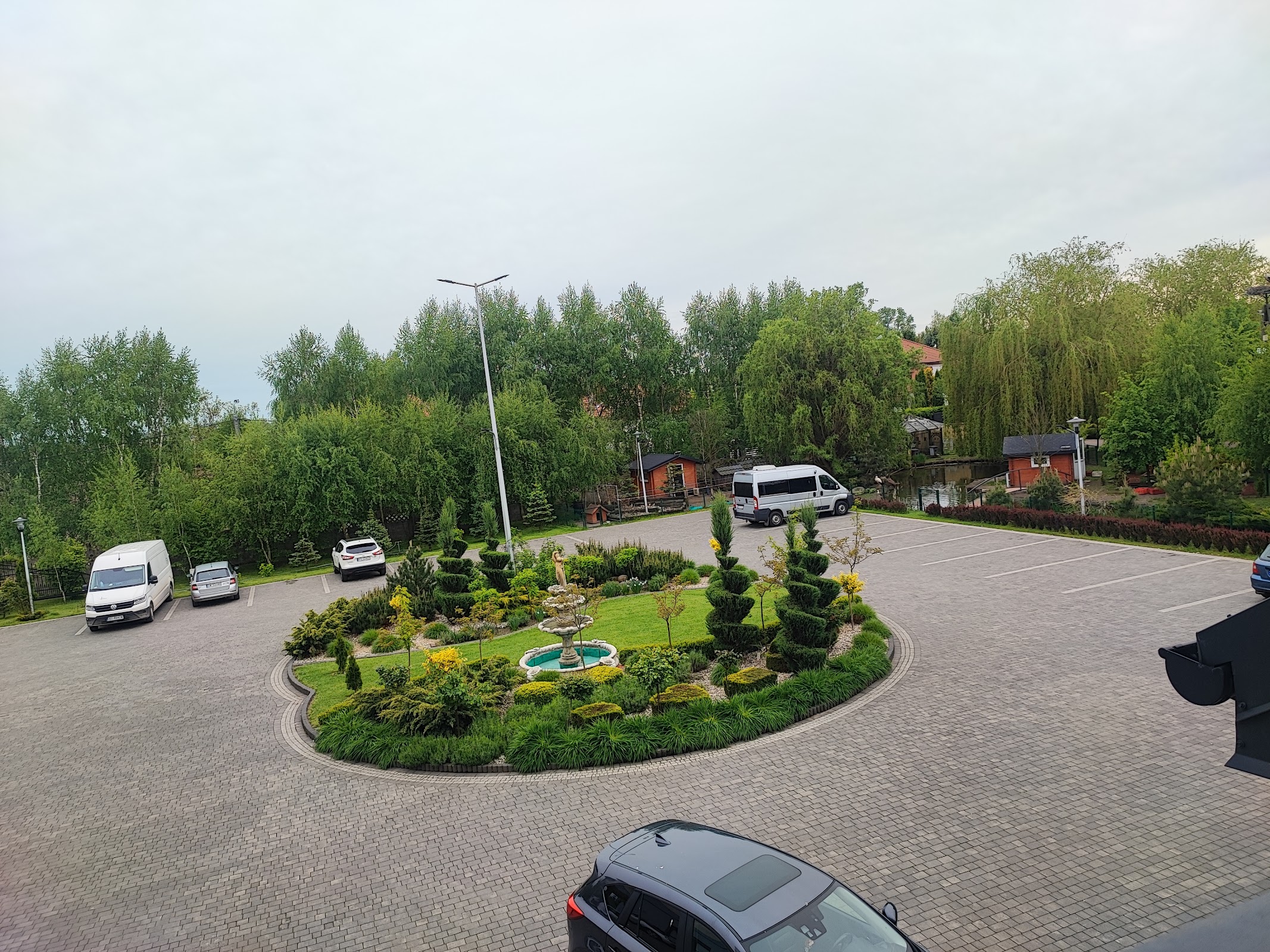 Zadbany ogród z fontanną i strzyżonymi tujami przed rezydencją